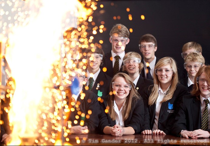 School science experiment with big yellow flash of flame with pupils looking on