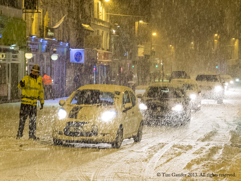 Police officer directs traffic in blizzard conditions in Bolton.