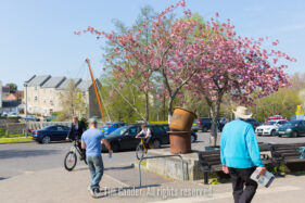 A view from the South side of the Cheese and Grain car park with the old foundry buckets, blossom trees, pedestrians, cyclists and cars and the Button Bridge in the distance.