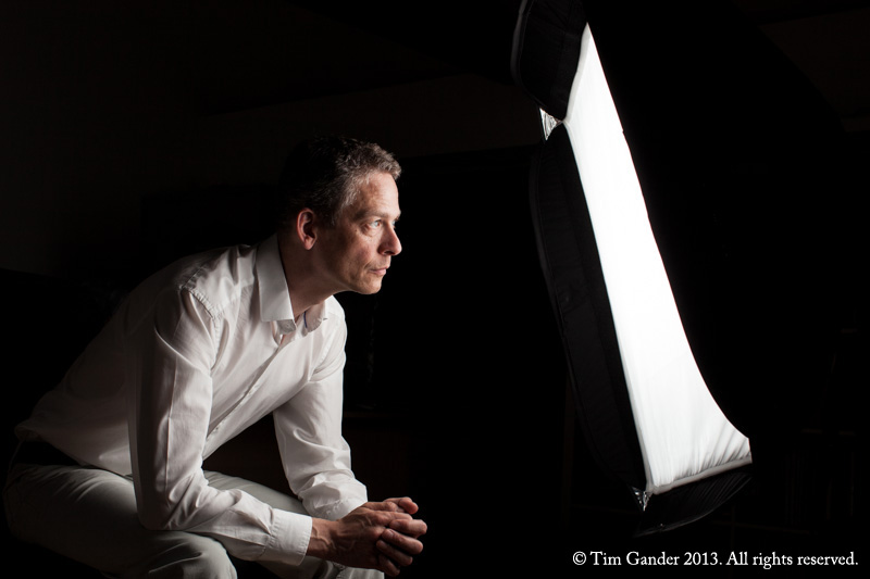 Tim Gander sits before a strobe softbox looking into the lit panel