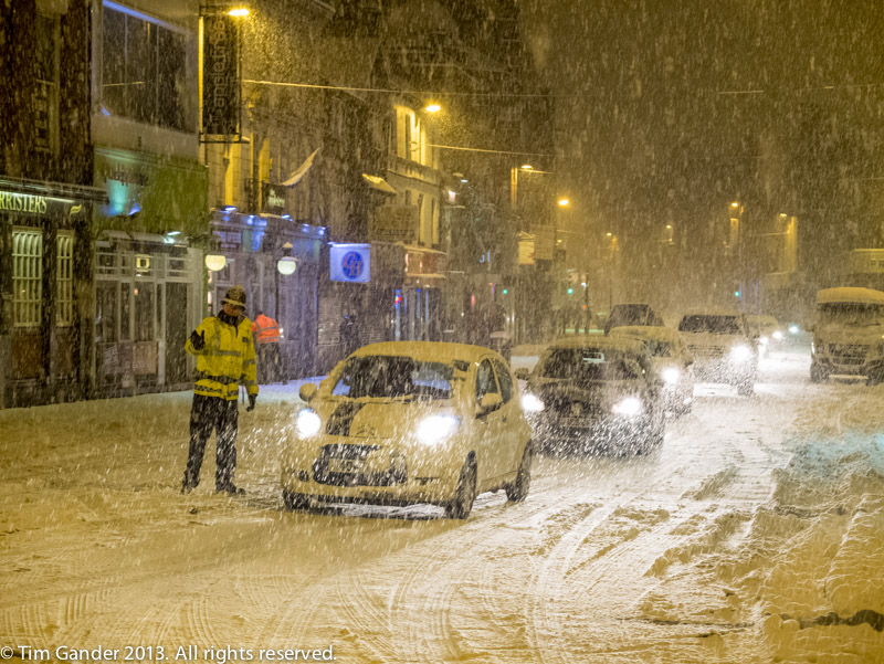 In Bolton a police officer directs traffic in heavy snow