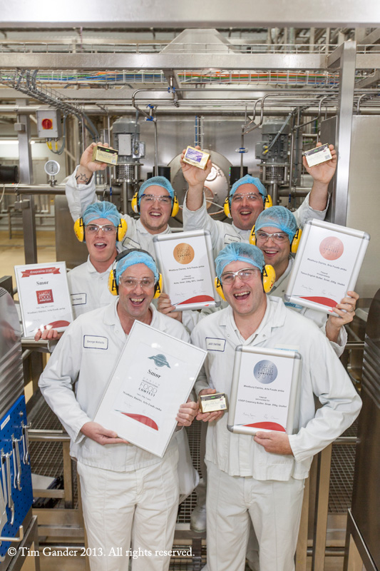 Westbury Dairy production team holding butter and certificates while standing on the production floor.