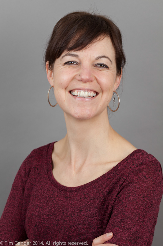 Smiling portrait against a grey background of author Sally M Gander