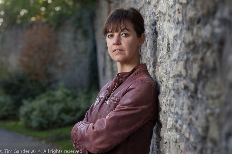 Frome-based author Sally M Gander poses by a stone wall in Frome