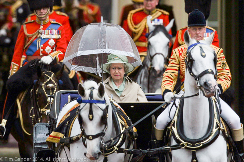 Queen Elizabeth II rides out in a horse-drawn carriage at the start of the Trooping the Colour ceremony and parade in London in 2001, protected by a transparent umbrella to protect her from the rain