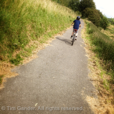 Angled photo of a boy on a bike on a cycle path