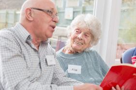 An elderly lady and her son sing and smile.