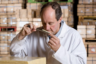 Brue Valley's Simon Clapp smells a core sample of cheese and grades it as it matures in this cooled store room.