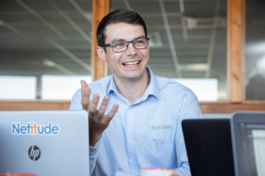 An IT executive speaking and gesticulating across a table with laptop.