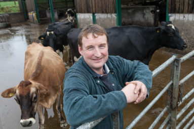 Arla dairy farmer Philip Cotterrell of Somerset poses at a gate with his herd around him.