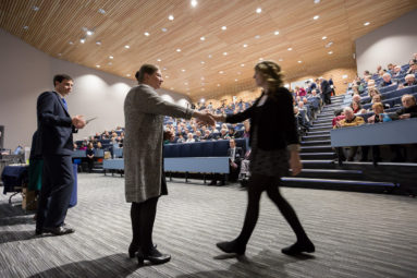 Vice Chancellor of University of Bath Glynis Breakwell shakes the hand of a student as she steps forward to receive her scholarship certificate in a packed lecture theatre.