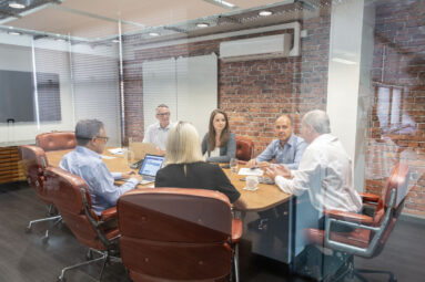 A business meeting seen through a glass office wall.