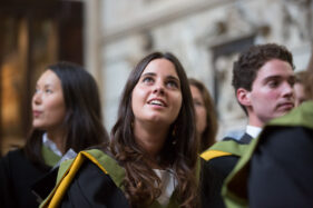 Original photo used for the University of Bath Impact Report cover shows a female graduate student looking upwards while waiting to collect her degree in Bath Abbey.