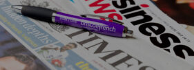 A Briscoe French branded pen lies on a pile of newspapers and magazines to illustrate the Briscoe French public relations service.