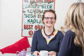 Michelle Gordon-Coles of Tea for Three sits chatting to a friend in a cafe over cups of tea.