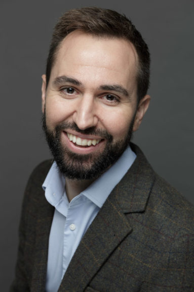 Smiling business portrait against a dark grey backdrop for BBA Architects of Bath.