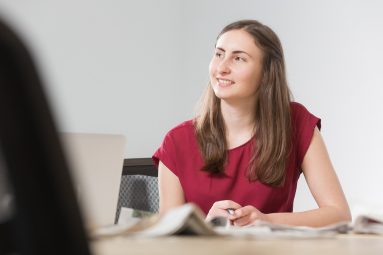 Charlotte Elmer of Briscoe PR seated at a table looking and smiling to someone off-camera.