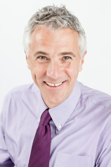 Smiling portrait of John Cooper in shirt and tie taken for Rowan Dartington, Bristol.