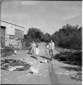 A family, mother, father, son and daughter walk through the derelict site.