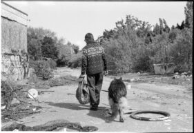 A man and his dog leave the site after exploring the rubbish for any valuable materials such as copper.