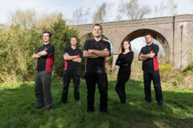 The Bristol Pest Controller team outside in a park in Bristol with a railway viaduct behind.