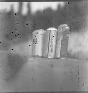 Discarded spray pint cans on a wall, highly degraded film results in black blobs and lines on the film.