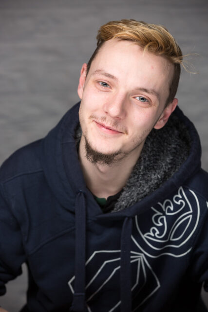 Portrait of a young man, smiling to camera, wearing a hoodie.