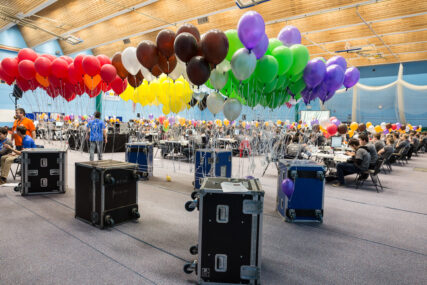 Different coloured balloons are tethered to roadie boxes as teams work in the background.