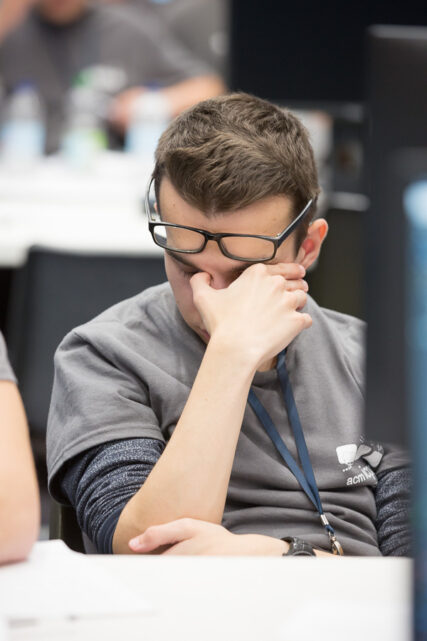 A male student raises his glasses to rub his tired eyes.