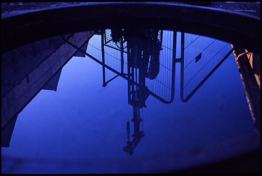 View of a drilling rig reflected in the water used to keep the drilling pipes lubricated.