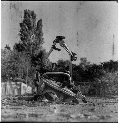 Degraded black and white photo of a vandalised pushchair seen from ground level.