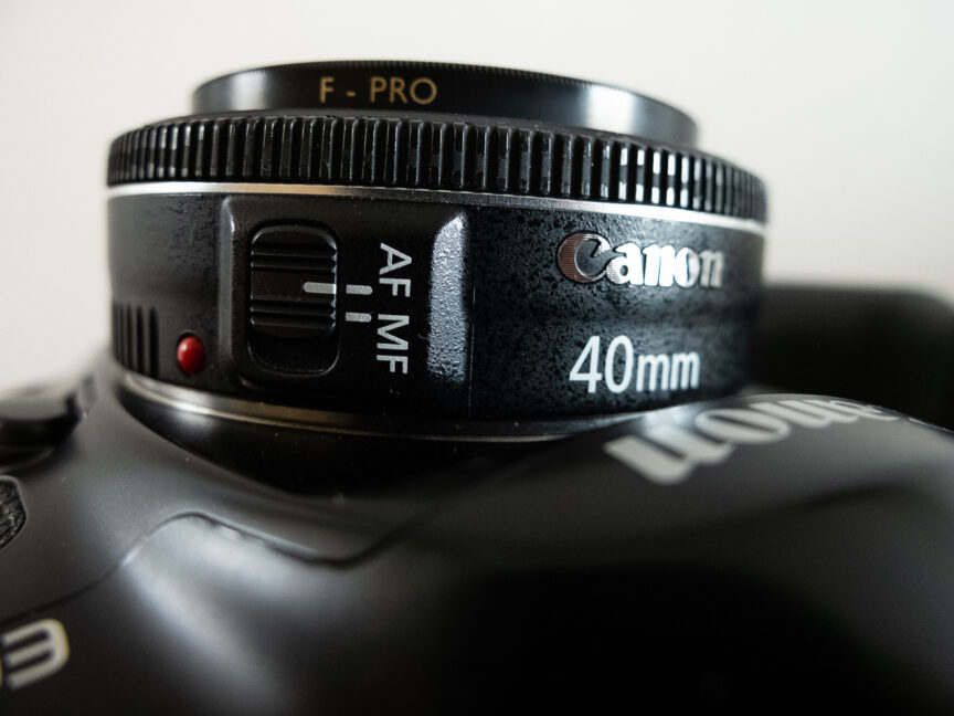 A very close side view of the Can EF 40mm f/2.8 lens showing the Canon logo, lens name and auto focus switch.