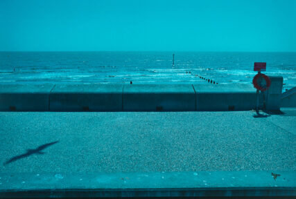 Landscape view looking out to sea across the width of the concrete promenade at Dymchurch in Kent.