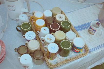 Looking down on a table with an electric kettle and a large assortment of mugs.