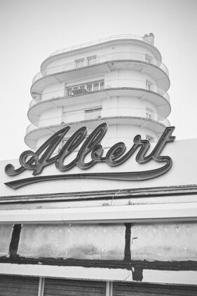 An Art Deco building rises up behind a large neon sign which says Albert in a handwritten-style font.