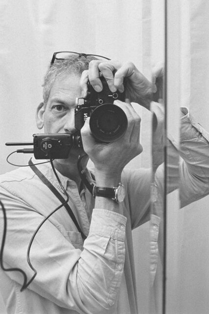 Self-portrait of Tim Gander with Nikon F2 camera in bathroom mirror.