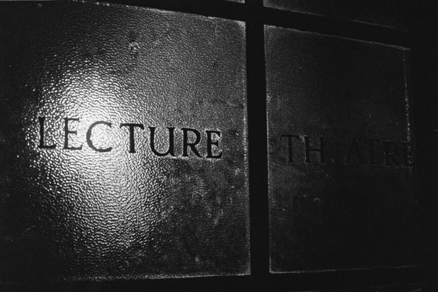 Black and white photo of the word "Lecture" written on obscuring glass, illuminated from behind by an unseen light bulb.