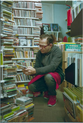 A shopper crouches to go through a selection of CDs.