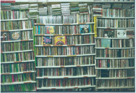 A flat-on view of several shelves of CDs which are bending under the weight.