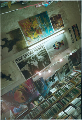 Looking up at the ceiling which has posters pinned to it, The Stone Roses being the central poster in the image.