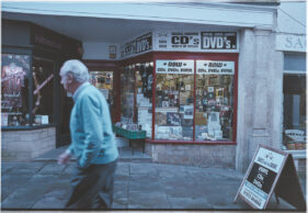 View of the shop front as a gentleman in a turquoise sweater walks past.