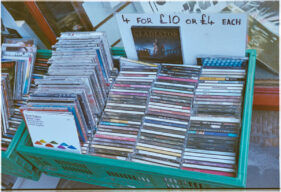 A box in the shop doorway containing CDs is marked "4 for £10".