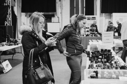 Two women at a table of secondhand cameras.