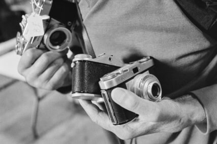 Close-up of a man's hands holding three cameras.