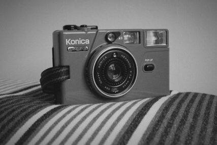 Photo of a Konica C35 EF3 camera on a stripy cushion.