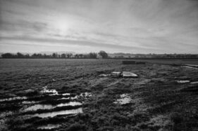 Black and white landscape of a waterlogged field with a dumped bed.