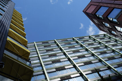 Wide angle view looking up at buildings C, A and B with blue sky beyond their rooflines.